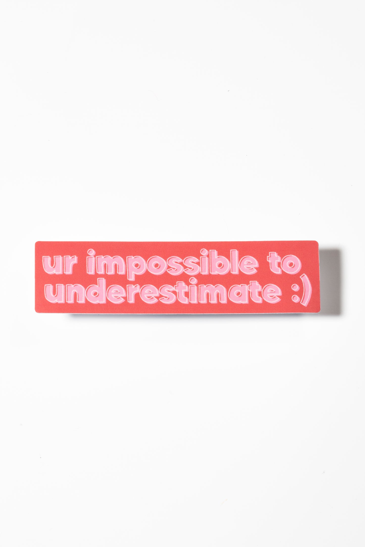 Pink and red sticker reads "ur impossible to underestimate" on a white background.