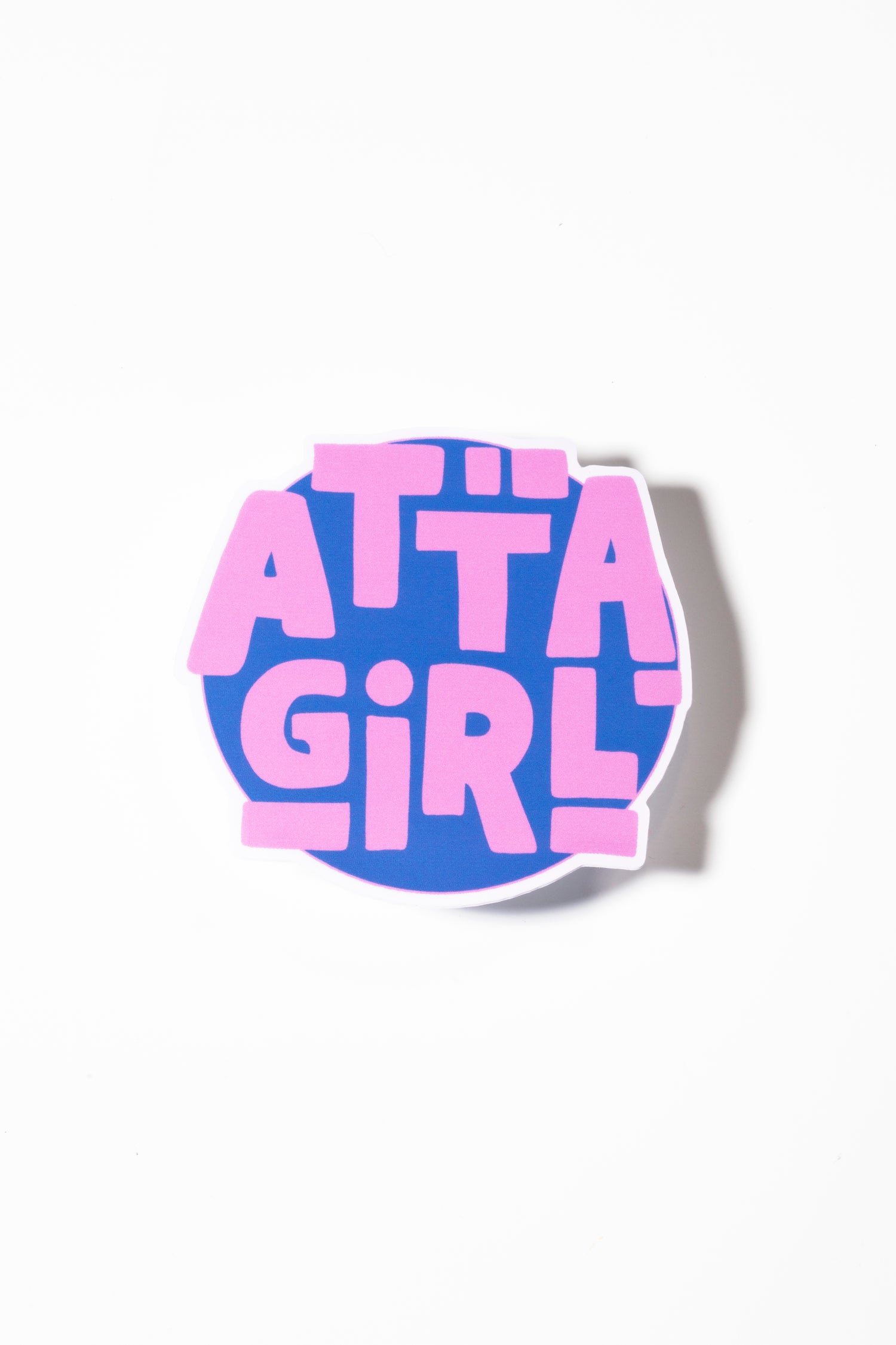 Sticker that reads "atta girl" on a blue background photographed on a white background.